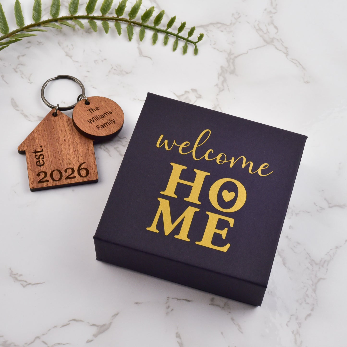 Keychain and 'welcome HOME' sign on a marble surface 