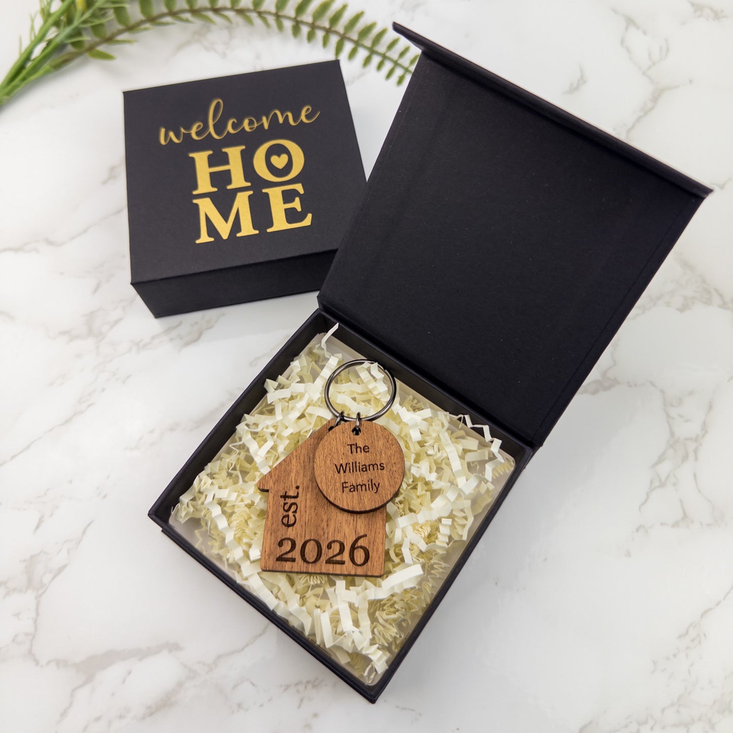 Personalized wooden keychain in a 'welcome HOME' box on a marble surface